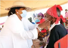  ?? — Pictures: John Manzongo ?? First Lady Auxillia Mnangagwa helps a senior citizen wear a reusable face mask during a Covid-19 interactiv­e awareness campaign in Binga yesterday.