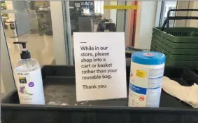  ?? GILLIAN FLACCUS ?? In this Sunday, March 29, 2020, photo, a sign posted at an entrance to a 365 Whole Foods store advises customers not to use their own bags while shopping in Lake Oswego, Ore. Just weeks earlier, cities and even states across the U.S. were busy banning straws, limiting takeout containers and mandating that shoppers bring reusable bags or pay a small fee. Grocery clerks are nervous that the virus could linger on reusable fabric bags and their unions are backing them up with demands to end plastic bag fees and suspend bag bans. The plastics industry has seized the moment, lobbying to overturn existing bans on single-use plastics.