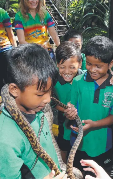  ?? Picture: ANNA ROGERS ?? WARM WELCOME: Bhutanese refugee students from Cairns West State School Sumina Rai, Saugat Rai and Manish Darjee check out Coco the scrub python at Cairns Zoom.