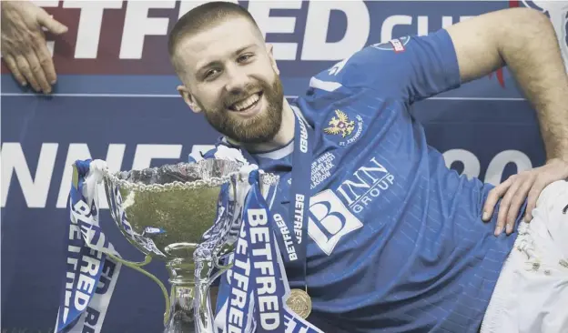  ??  ?? 0 Shaun Rooney celebrates with the trophy after his first-half goal gave St Johnstone victory over Livingston in the Betfred Cup final at Hampden yesterday