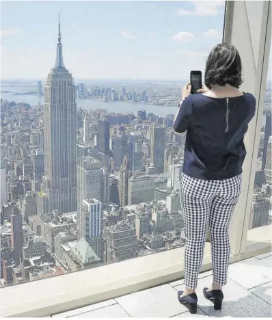  ?? Timothy A. Clary / AFP ?? Una mujer toma una foto del Empire State Building y de parte del ‘skyline’ de Manhattan.