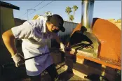  ??  ?? Chef Jose Hernandez checks on several pizzas in a clay oven in a makeshift backyard pizza kitchen on April 3, in Scottsdale, Ariz.