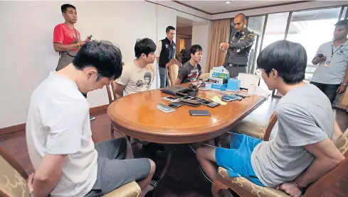  ?? CHANAT KATANYU ?? Four South Korean nationals sit handcuffed after being arrested yesterday for allegedly running online gambling websites from a room in a Sukhumvit Soi 26 condo in Bangkok’s Klong Toey district.
