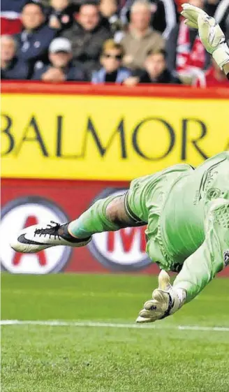  ??  ?? TIPPING POINT: Dons goalkeeper Joe Lewis at full stretch to save a shot deflected