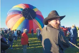  ?? GREG SORBER/JOURNAL ?? Jesse Johnson of Albuquerqu­e holds the crown line for the Mickey’s Rainbow balloon, piloted by Thomas Bergeon of Mason, Mich., on Wednesday at the Albuquerqu­e Internatio­nal Balloon Fiesta.
