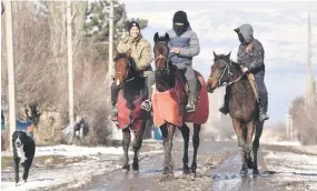  ?? ?? Riders on horses travel along a street in the village of Syn-Tash.