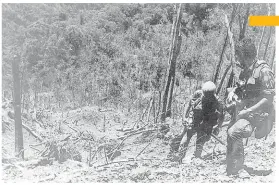  ?? [WIKIPEDIA] ?? A U.S. Army photograph­er and assistant climb through the devastated landscape on Vietnam’s Dong Ap Bia after the battle of Hamburger Hill in May 1969.