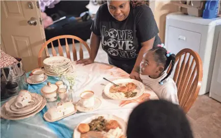  ?? PHOTOS BY DENNY SIMMONS/THE TENNESSEAN ?? La’Monia Merritt says grace before her kids, Faith, 4, and K.J, 10, eat dinner at their home in Hermitage. Merritt celebrates her life now with her two young children after the Homeless Education Resource Office, also known as HERO, offered her resources to reclaim her life.