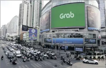  ?? PHOTO: EPA-EFE ?? Vehicles transit next to a large-scale screen displaying a logo of Grab (formerly GrabTaxi), a taxi hire mobile phone app. Toyota announced in March that it would invest $1 billion in the ride-hailing company.