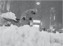  ??  ?? A powerful blizzard pounded the MidAtlanti­c and the Northeast in America early yesterday, prompting flight cancellati­ons, school closures and warnings from city and state officials to stay off the roads. In the picture, a worker clears snow in Times Square, New York yesterday