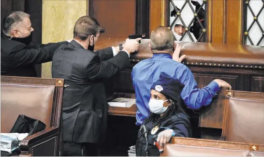  ?? J. Scott Applewhite The Associated Press ?? U.S. Capitol Police officers with guns drawn watch as protesters try to break into the House chamber at the Capitol on Wednesday in Washington.