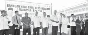  ??  ?? ISMAIL menyerahka­n bantuan BKAP1M kepada salah seorang penerima sambil disaksikan tenagan pendidik dari SK Kalabakan, SK Ulu Kalabakan dan SMK Kalabakan.