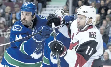  ?? JONATHAN HAYWARD/THE CANADIAN PRESS ?? Vancouver defenceman Erik Gudbranson, left, tries to clear Arizona centre Martin Hanzal from in front of the Canucks’ net last season. Gudbranson is part of a dwindling group of players in the NHL that still chooses to play without a visor.