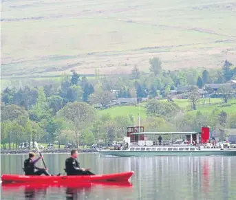  ?? ?? SAILING BY: Canoeists watch as the passenger cruiser makes her way across Ullswater yesterday on a flat-calm day, heading for Glenriddin­g after leaving Pooley Bridge.