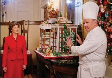  ?? (File Photo/AP/Manuel Balce Ceneta) ?? First lady Laura Bush listens to White House pastry chef Roland Mesnier explain the components of the White House Gingerbrea­d House on Dec. 4, 2003, in the State Dining Room.