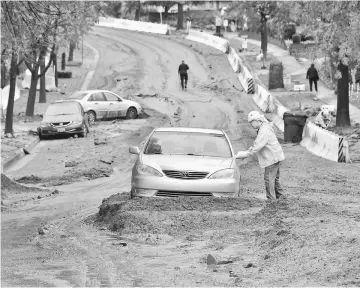  ??  ?? File photo shows a man approaches his car stuck in the mud which washed down Melcanyon Road in Duarte, California in the foothills on the San Gabriel Mountains, as the biggest rain storm of the season hits southern California. — AFP photo