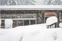  ?? BROOKE HESS-HOMEIER / AP ?? Snow covers the landscape in front of a store, Saturday in Truckee, Calif. A powerful blizzard howled in the Sierra Nevada as the biggest storm of the season shut down a long stretch of Interstate 80 in California and gusty winds and heavy rain hit lower elevations, leaving tens of thousands of homes without power.