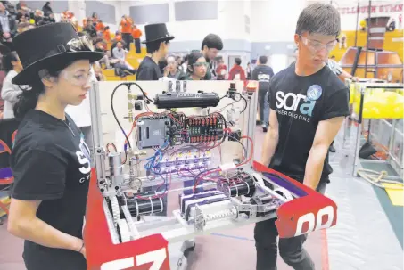  ??  ?? Above: Members of the Ruth Asawa School of the Arts Cyberdrago­ns carry their robot into the arena. Left: Seyhmus Aca (left) watches his Sultans of Turkey teammates compete in a qualifying match at the First Robotics Competitio­n.