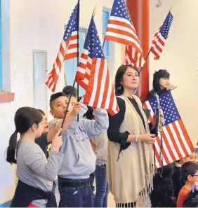  ?? JIM THOMPSON/JOURNAL ?? Teacher Carol Carriage stands with students from her fifth-grade class at Barcelona Elementary School as they wave flags and celebrate first-grade teacher Shirley Barreto, who took the Oath of Allegiance on Friday to become a U.S. citizen.