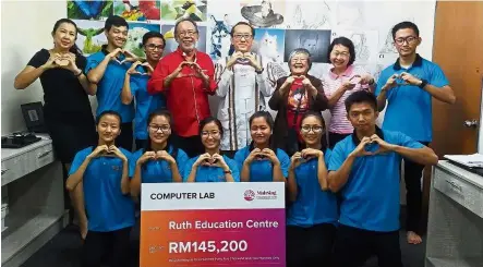  ??  ?? (Back row, fourth and fifth from left) Syed Norulzaman and Moey pose for a group picture after the presentati­on of a mock checque to set up the computer lab for refugee children.