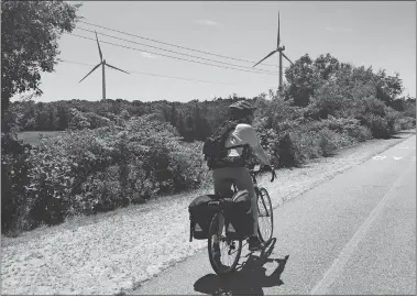  ?? LORI RILEY VIA AP ?? Above, Associated Press reporter Pat Eaton-Robb rides past windmills July 13 on the Phoenix Trail in Fairhaven, Mass. The trail is part of the East Coast Greenway, a planned 3,000-mile collection of trails from Maine to Florida that is about 41 percent complete in New England.