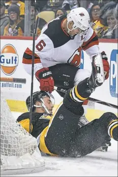  ??  ?? Derick Brassard, playing his first game in a Penguins uniform, is upended by New Jersey’s Andy Greene.