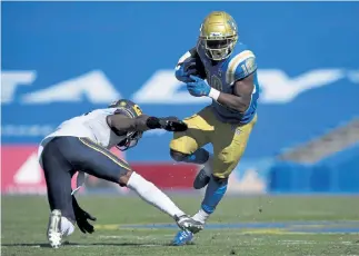  ?? Kelvin Kuo, The Associated Press ?? UCLA running back Demetric Felton, right, runs the ball past California safety Elijah Hicks during Sunday’s hastily- scheduled game. UCLA won 34- 10.