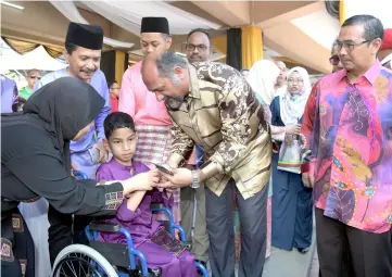  ?? — Bernama photo ?? Gobind (second right) distribute­s ‘Duit Raya’ to a boy at the ministry’s Raya open house.