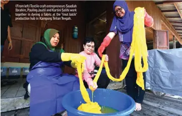  ??  ?? (From left) Textile craft entreprene­urs Saadiah Ibrahim, Pauling Jauhli and Kartini Salihi work together in dyeing a fabric at the ‘linut batik’ production hub in Kampung Telian Tengah.