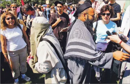  ?? ADRIAN WYLD/ CP ?? Mubin Shaikh, right, and his wife Joanne Siska stand back-to-back among protestors as they defend the use of sharia law in family arbitratio­n in Ontario. About 300 people turned up at Queen’s Park for the protest.