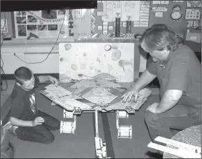  ?? Brittany Williams/News-Times ?? Assembly: Mike Means, on right, guides Retta Brown student Arthur Rodgers while assembling a rover model designed by his classmates.