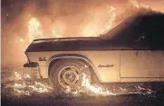  ?? [AP PHOTO] ?? Flames from a wildfire consume a car Saturday near Oroville, Calif. Evening winds drove the fire through several neighborho­ods leveling homes in its path.