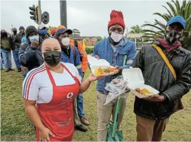  ?? Picture: WERNER HILLS ?? FOOD FOR THOUGHT: Liya Yisaka hands out food to the workers who stand on the side of the road hoping to get the odd painting or maintenanc­e job. Mike Gwezuva, centre, and Zukisa Siqongana, far right, were delighted to tuck into the hot meal