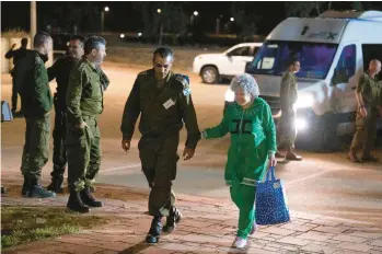  ?? IDF ?? Ruti Munder, a released Israeli hostage, walks with an Israeli soldier shortly after her arrival in Israel on Friday.