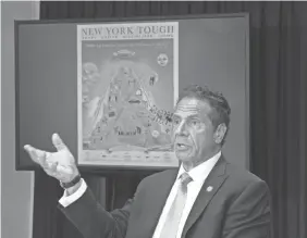  ?? DON POLLARD/OFFICE OF GOV. ANDREW CUOMO ?? Gov. Andrew Cuomo displays a new poster on New York’s fight against coronaviru­s during a briefing Monday.