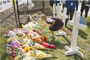  ?? AP PHOTO/JOHN AMIS ?? A young girl places an item at a growing memorial March 28 at an entry to Covenant School in Nashville.