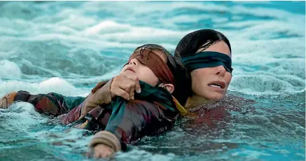  ??  ?? Sandra Bullock leads ‘‘Girl’’ (Vivien Lyra Blair) to safety in Bird Box.