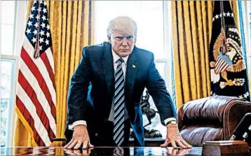  ?? ANDREW HARNIK/AP ?? President Donald Trump poses for a photograph at his desk Friday. His administra­tion will mark its 100th day Saturday.