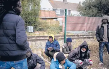  ?? CHRISTOPHE ENA /AP ?? Migrants wait for food to be distribute­d last month at a camp in Calais, located in northern France.