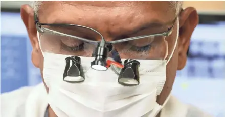  ?? MICHAEL SEARS/MILWAUKEE JOURNAL SENTINEL ?? Dentist Pablo Fernandez uses a headlamp and magnifiers attached to his glasses as he does a dental filling for a patient at the Lake Area Free Clinic in Oconomowoc.