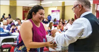  ??  ?? T.L. Waggoner Elementary teacher Olivia Silva (left) smiles as she receives a prize from a drawing during the ninth annual Welcome Back Teachers Luncheon event hosted by the Imperial Chamber of Commerce on Tuesday afternoon at Frank Wright Middle School in Imperial. PHOTO VINCENT OSUNA