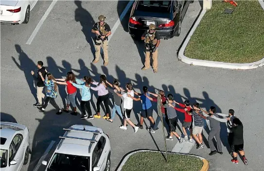  ?? PHOTO: GETTY IMAGES ?? Students at Marjory Stoneman Douglas High School are led to safety by police after a shooting spree by a former student, which left 17 people dead.