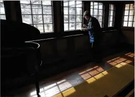  ??  ?? Cecil Fields from Columbus, one of the volunteers cleaning and getting the Westcott House ready to reopen for tours on Saturday, cleans around the windows in the front room of the Springfiel­d house that was built by Frank Lloyd Wright.