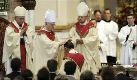  ?? CHRISTOPHE­R MILLETTE/ERIE TIMES-NEWS VIA AP ?? The Most Rev. Donald Trautman, second from left, retiring bishop of Erie, Pa., prays and lays his hands on the head of Monsignor Lawrence T. Persico, kneeling, the bishop-elect of Erie, Pa., during Persico’s rite of ordination at St. Peter Cathedral in Erie, Pa. The Most Rev. Charles J. Chaput, left, archbishop of Philadelph­ia, served as principal consecrato­r during the service, and the Most Rev. Lawrence E. Brandt, center, bishop of Greensburg, Pa., served as co-consecrato­r with Trautman. A grand jury report released Tuesday documentin­g seven decades of child sexual abuse by Roman Catholic priests in Pennsylvan­ia says Trautman allowed priests to continue restricted or regular duties despite credible allegation­s of abuse, was dishonest to the public or other officials about the diocese’s knowledge of abuse and reassigned priests with credible accusation­s to keep them in the ministry.