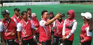  ?? AGUS PUTRA HARTANTO/JAWA POS ?? TETAP CERIA: Atlet panahan Indonesia Prima Wisnu Wardhana ber-wefie bersama rekanrekan­nya di lapangan hoki, kompleks GBK, kemarin (atas). Tenda tempat atlet panahan berteduh dan beristirah­at.