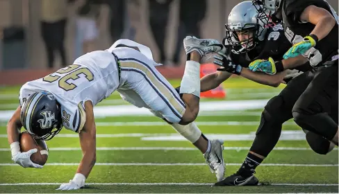  ?? JIM WEBER/THE NEW MEXICAN ?? Demons running back Martell Mora, left, is tripped up by the Jaguars’ Angelo Baker on Friday at Jaguar Field. Santa Fe High, led by Mora’s five touchdowns, outran the Jaguars to a 48-28 win.