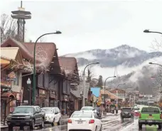  ?? ANDREW NELLES, THE TENNESSEAN ?? Rain falls as cars drive Tuesday through downtown Gatlinburg, Tenn. The community was ravaged by wildfires last week.