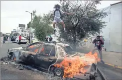  ?? aP-ringo h.W. Chiu ?? A person jumps on a burning police vehicle in Los Angeles on Saturday.