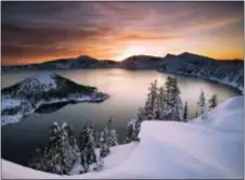  ?? MARC ADAMUS — THE REGISTER-GUARD VIA AP, FILE ?? The sun rises over Crater Lake, Ore., in Crater Lake National Park. Crater Lake lies in the caldera of an ancient volcano called Mount Mazama that collapsed 7,700 years ago, according the the National Parks Service. It is the deepest lake in the United...