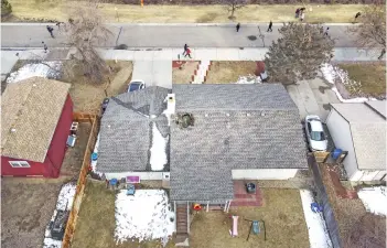  ?? — AFP photos ?? An aerial view from a drone shows people walking past a home with a hole in the roof from falling debris from an United Airlines airplane engine in Broomfield, Colorado.